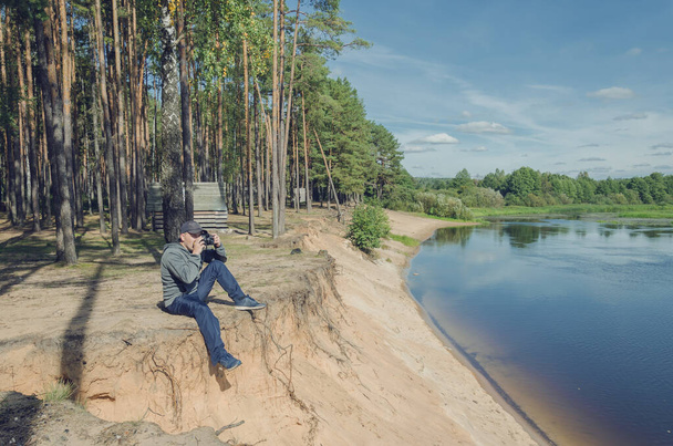Photographer relaxes in nature near the river. Beautiful landscape outdoor recreation. - Fotoğraf, Görsel