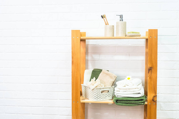 Badezimmer mit Holzregalen für Kosmetikprodukte und Handtücher. - Foto, Bild