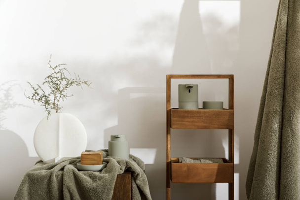 Modern aesthetic bathroom accessories in eucalyptus light  green shade. Organic cotton bath towels, minimalistic Scandinavian style vase, sensor soap and lotion dispenser  on solid oak stump. Daily body care, spa and wellness  bathroom concept - Photo, Image