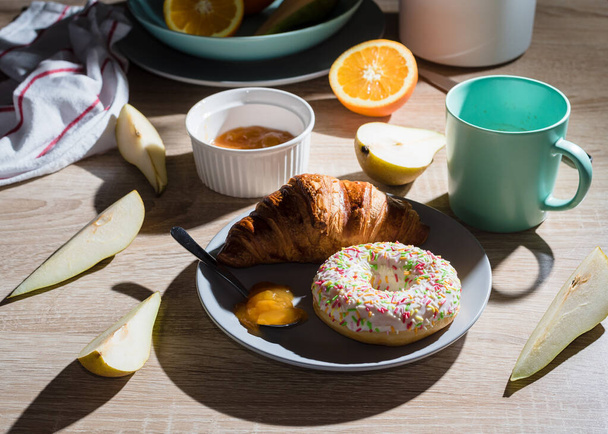 Terveellinen aamiainen. Croissant, donitsi, kahvi, hilloa, hedelmiä: appelsiinit ja päärynät. Yläkuva - Valokuva, kuva