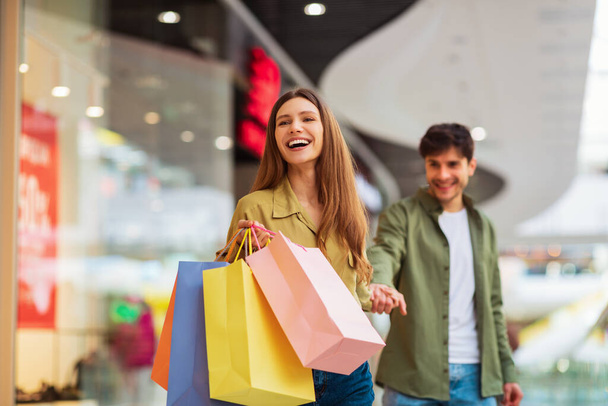 Freudig ehefrau tragen taschen ziehen ehemann shopping zusammen im mall - Foto, Bild