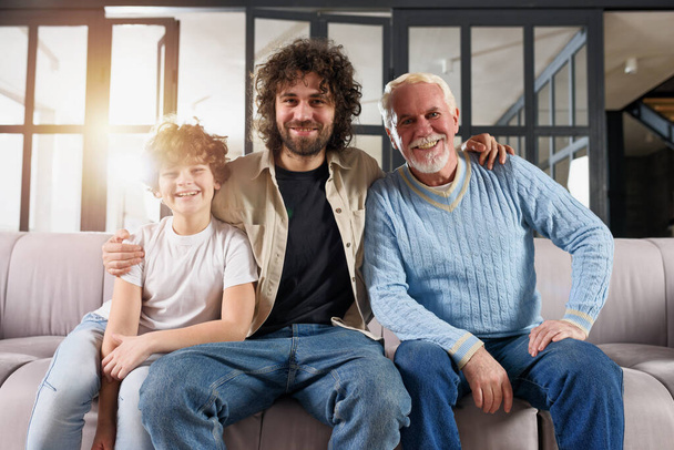 Isoisä, isä ja lapsenlapsi, jotka nauttivat sohvalla yhdessä kotona. - Valokuva, kuva