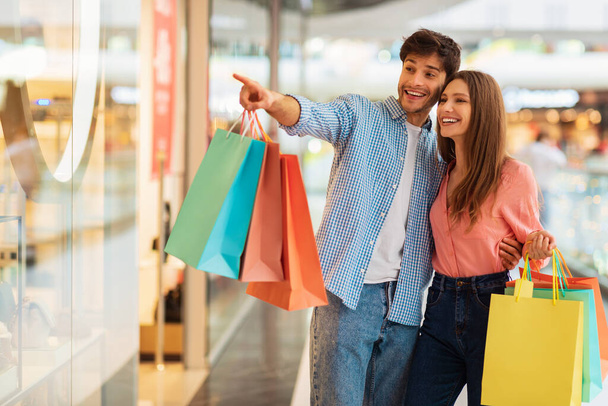 Couple faisant du shopping ensemble, mari pointant du doigt à la boutique dans le centre commercial - Photo, image