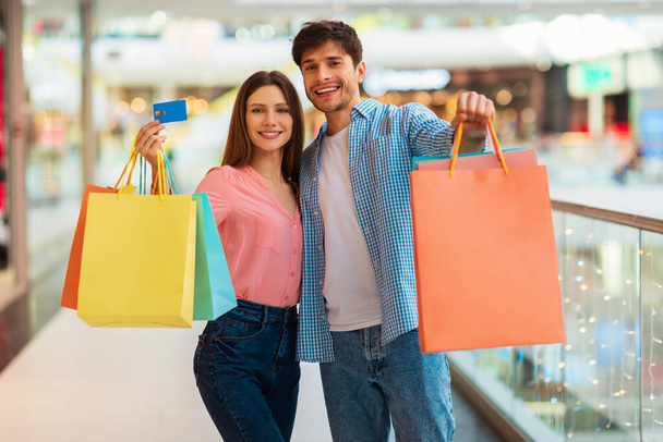 Eşler Kredi kartını ve alışveriş torbalarını alışveriş merkezinde gösteriyor - Fotoğraf, Görsel