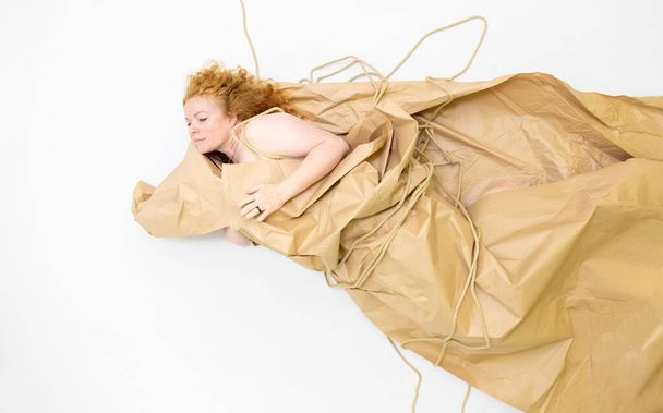sexy, mature redhead woman wrapped in wrapping paper and string, unwraps herself as gift package, flying like an angel, copy space - Fotografie, Obrázek