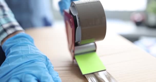 Εργαζόμενος σφράγιση κουτί από χαρτόνι με ταινία χρησιμοποιώντας ειδικό μηχάνημα closeup 4k ταινία - Πλάνα, βίντεο