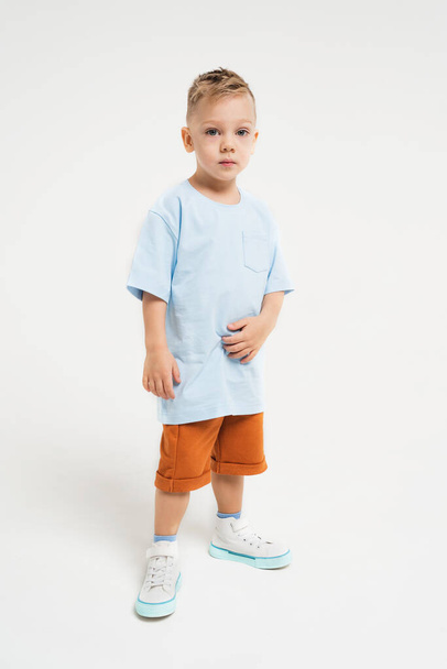 El chico lleva un chándal. Un niño con ropa monocromática sobre un fondo monocromático. foto vertical con un niño - Foto, imagen