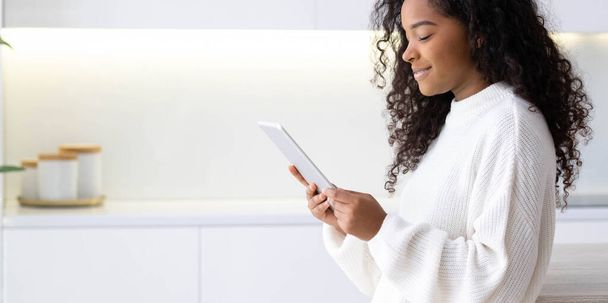 Banner African American Girl usando o tablet iPad em casa pressionando o dedo, lendo internet de mídia social, digitando texto ou fazendo compras online. Freelancer Trabalhando remotamente on-line em casa. - Foto, Imagem