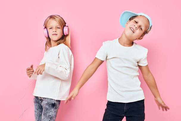 帽子を被った男の子と女の子がピンク色の背景で遊んでいます - 写真・画像