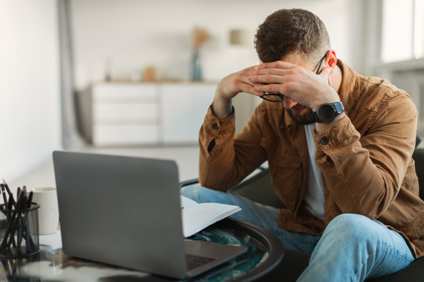 Homme stressé à l'ordinateur portable touchant la tête ayant des problèmes d'affaires à l'intérieur - Photo, image