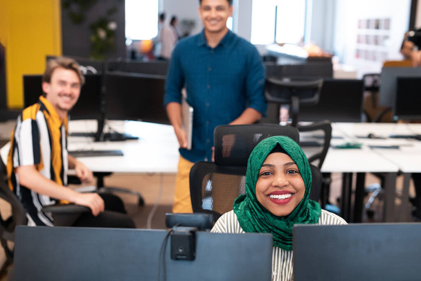 Equipo de negocios de startups multiétnicas Mujer árabe con un hijab en la reunión en la moderna oficina de planta abierta lluvia de ideas interior, trabajando en el ordenador portátil y de escritorio. Enfoque selectivo. Alta calidad - Foto, imagen