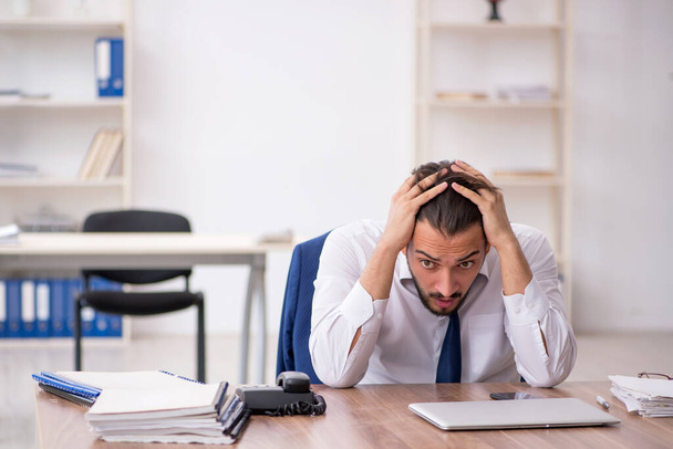 Joven empleado masculino descontento con el trabajo excesivo en la oficina - Foto, imagen