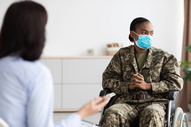 Femme militaire noire déprimée en fauteuil roulant ayant une séance de thérapie avec un psychologue - Photo, image
