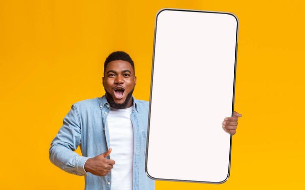 Fröhlicher Kerl zeigt großen weißen leeren Smartphone-Bildschirm und gefällt - Foto, Bild