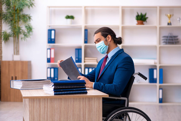 Jeune employé handicapé pendant une pandémie sur le lieu de travail - Photo, image