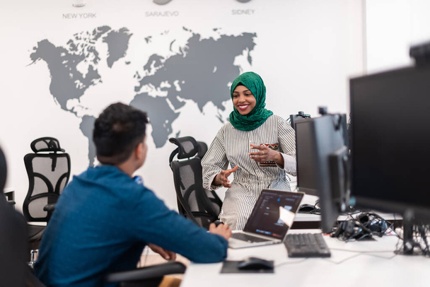 Multiethnic startup business team Arabian woman wearing a hijab on meeting in modern open plan office interior brainstorming, working on laptop and desktop computer. Selective focus. High-quality - 写真・画像