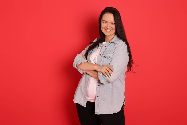 Beautiful overweight woman with charming smile on red background - Fotó, kép