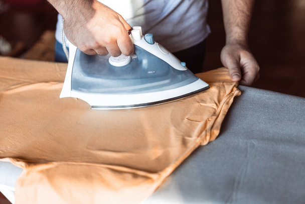 close-up of a mans hands ironing a T-shirt - Foto, afbeelding