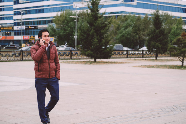 asian man walking in the street with phone. - Φωτογραφία, εικόνα
