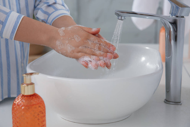 Woman washing hands with liquid soap in bathroom, closeup - Foto, Bild