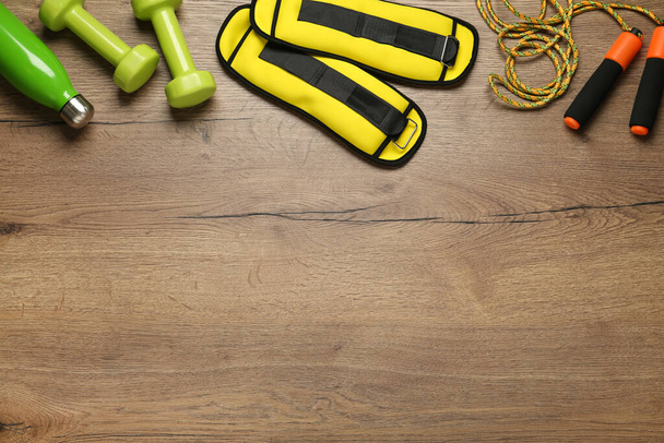 Yellow weighting agents and sport equipment on wooden table, flat lay. Space for text - Photo, Image