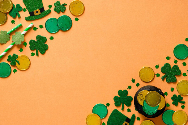 St Patricks Day banner with gold coins, clover shamrock leaves, pot of gold, leprechauns hats on orange background. Flat lay, top view. Saint Patricks Day greeting card mockup. - Fotoğraf, Görsel