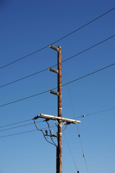 Electricity distribution pylon and power lines under blue sky - Foto, imagen