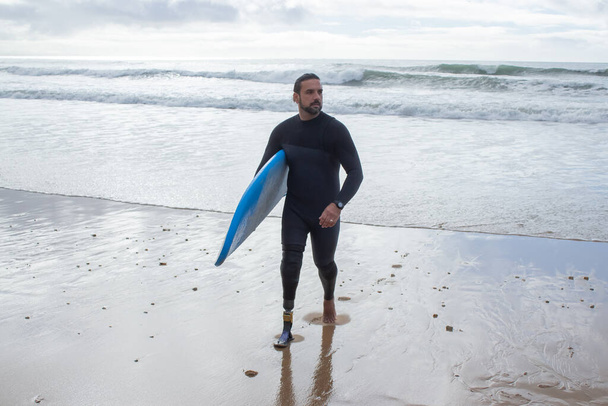 Portrait of dark-haired man training on beach alone - Foto, Imagen