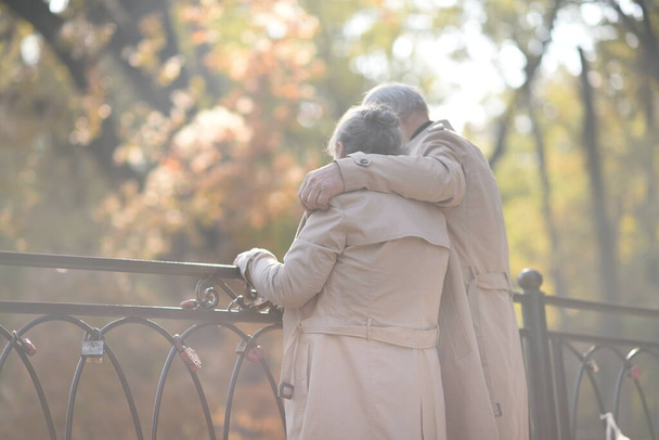 stary emerytowany szczęśliwy kochający przytulanie para spacer w jesienny park - Zdjęcie, obraz