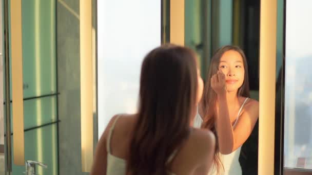 footage of beautiful young asian woman doing makeup while looking at mirror in bathroom - Footage, Video