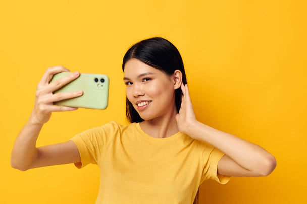 woman with a smartphone in hands fun emotions close-up yellow background unaltered - Foto, Imagen
