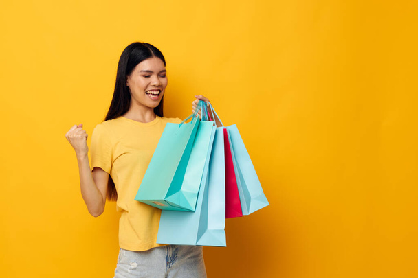 Charming young Asian woman with packages in hands shopping isolated background unaltered - Φωτογραφία, εικόνα