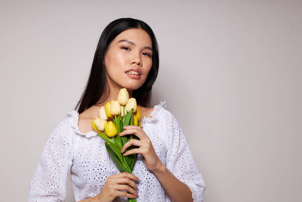 woman with Asian appearance romance bouquet of flowers near the face light background unaltered - Fotó, kép