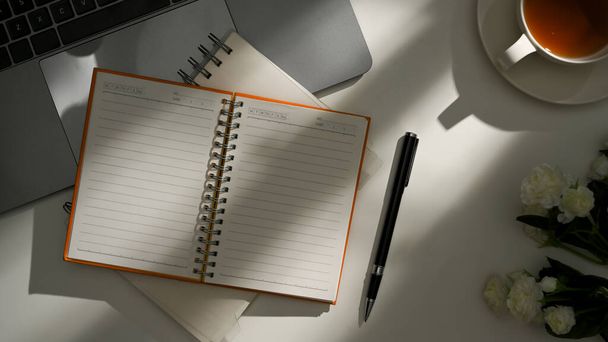 Bildung und Bürokonzept, Ein offenes Notizbuch mit leeren Seiten und Büromaterial auf dem Tisch im Schatten der Sonne. Ansicht von oben - Foto, Bild
