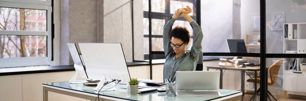 Arms Stretch Exercise Sitting At Desk In Office - 写真・画像