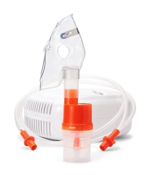 白い背景に隔離された圧縮機のニブライザーのためのカップをアトマイズする上で呼吸マスク。喘息および呼吸器疾患の吸入療法のための医療機器. - 写真・画像