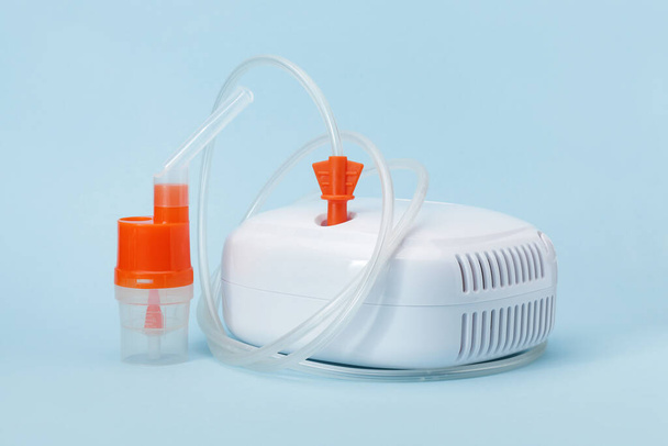 Atomizační kelímek s náustkem nebulizátoru pro inhalátor kompresoru na modrém pozadí. Zdravotnické vybavení pro inhalační léčbu astmatu a respiračních onemocnění. - Fotografie, Obrázek
