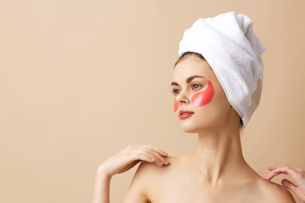 mooie vrouw roze vlekken op het gezicht met een handdoek op het hoofd geïsoleerde achtergrond - Foto, afbeelding
