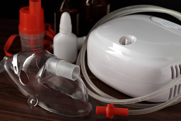 Respirační maska pro rozprašovač kompresoru na stole, malá hloubka zaostření. Zdravotnické vybavení pro inhalační léčbu astmatu a respiračních onemocnění. - Fotografie, Obrázek