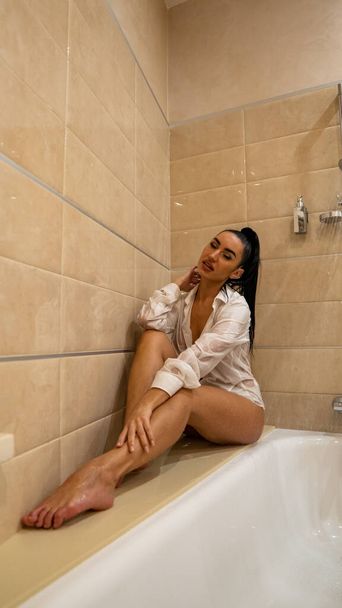 красивая молодая женщина голая только в одной мокрой мужской рубашке позирует в ванной комнате, фото - Фото, изображение