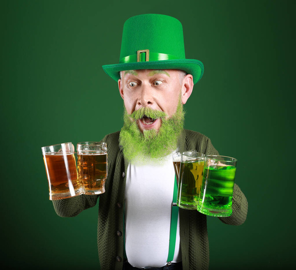 Vtipný dospělý muž s velkou hlavou a sklenicemi piva na zeleném pozadí. Oslava svatého Patrika - Fotografie, Obrázek