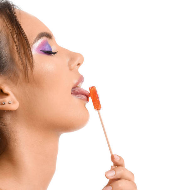 かなり若いです女性食べるオレンジロリポップ上の白い背景 - 写真・画像