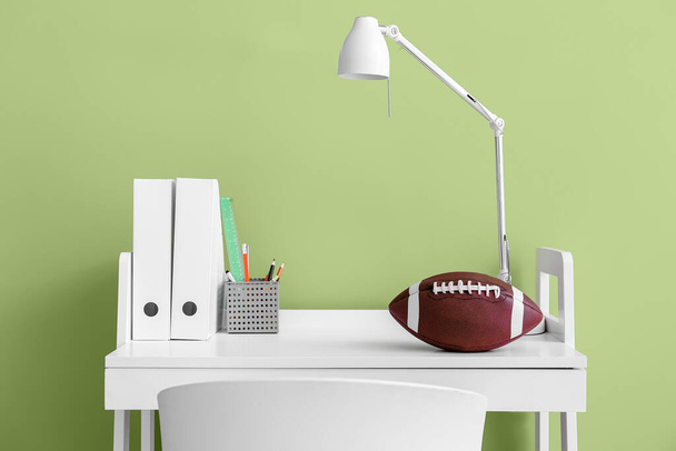 Modern workplace with folders and rugby ball near green wall - Valokuva, kuva