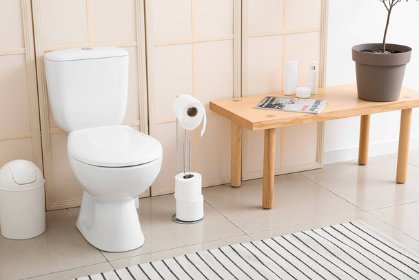 Bin, toilet bowl, paper holder, table with magazine and bath supplies - Zdjęcie, obraz