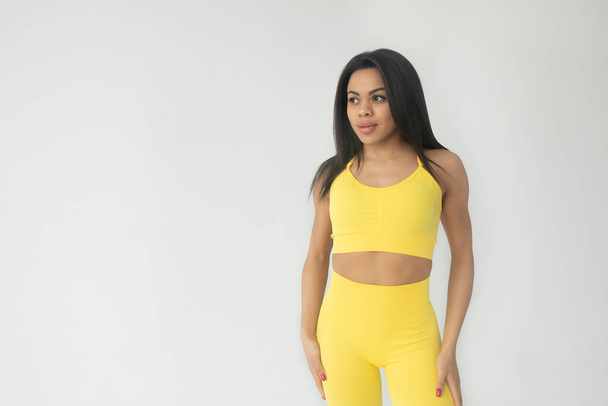 attractive young fit african american woman in yellow sportswear posing in studio  - Foto, Bild