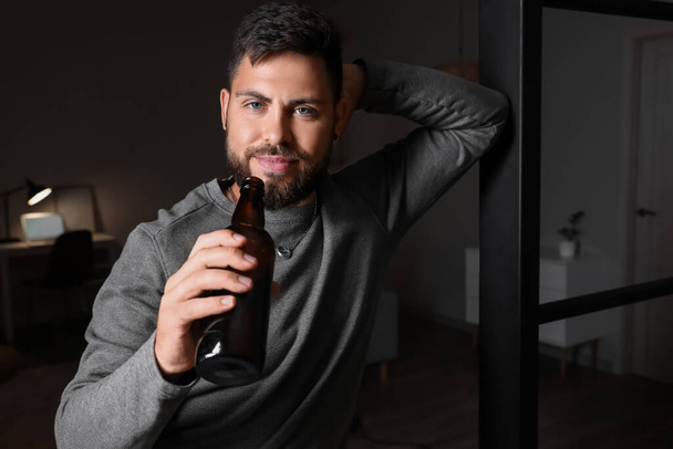 Akşamları evinde bira şişesi olan sakallı genç bir adam. - Fotoğraf, Görsel