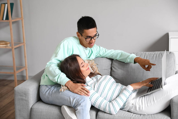Young man and his wife with laptop shopping online on sofa at home - Foto, Imagem