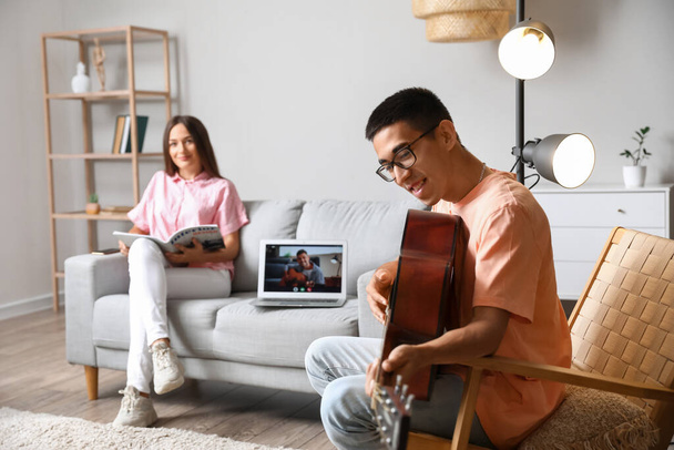 Nuori mies ottaa online kitara oppitunti kotona - Valokuva, kuva