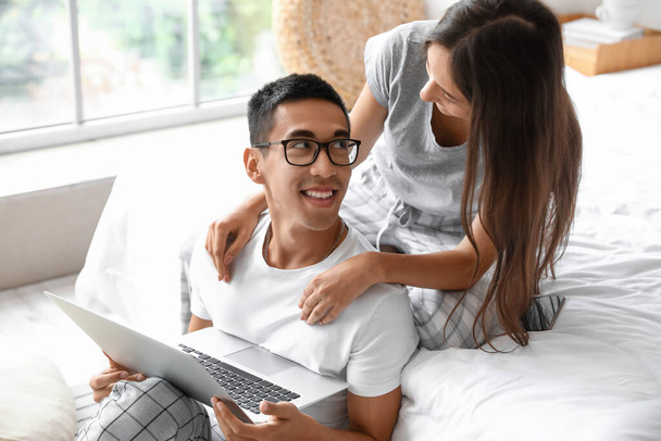 Junger Mann mit Laptop und Freundin im Schlafzimmer - Foto, Bild