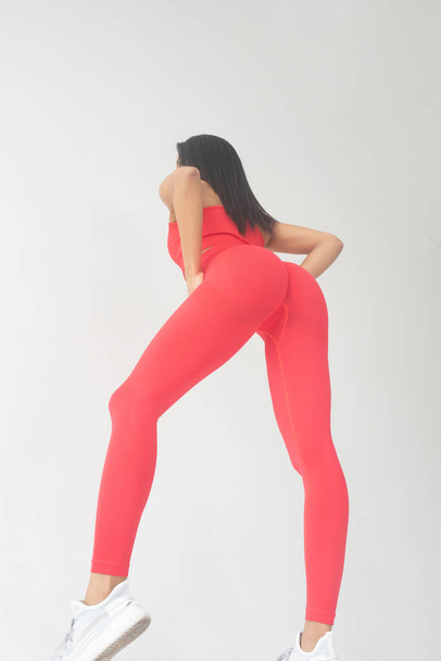 back view of young fit african american woman in red sportswear posing in studio  - Fotó, kép